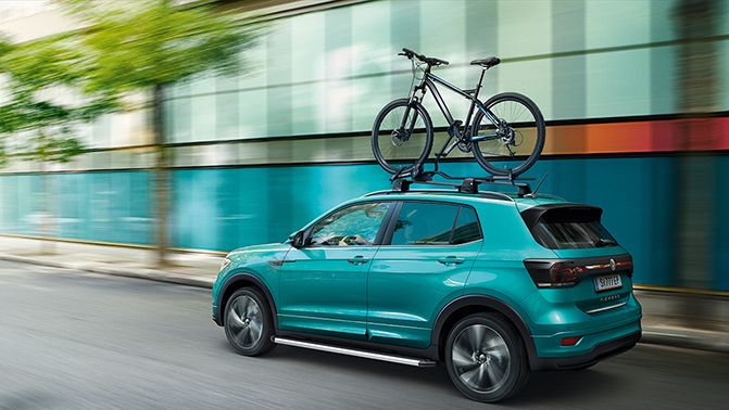 Fahraufnahme eines VW T-Cross in türkis mit Fahrrad am Dachträger